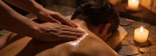 Professional tantric massage session in Oslo with slow conscious touch on the upper back in a warm candlelit studio